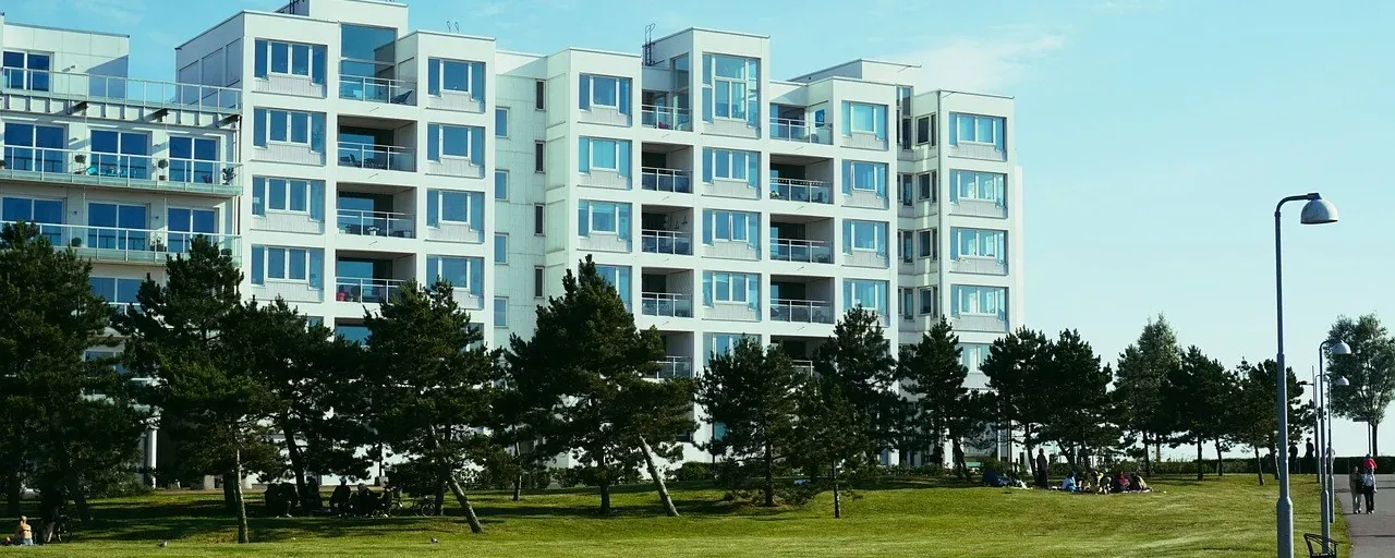 Ljusa svenska flerbostadshus med balkonger intill en grön park